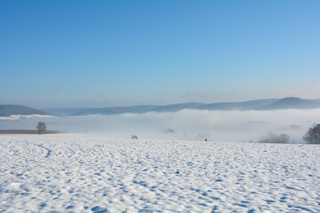 Fototapeta na wymiar Snow landscape with fields and fog in the valley