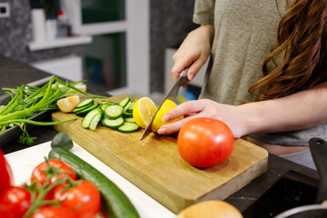Young woman cut lemon for preparing salad in kitchen, close up