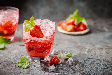 Refreshing summer drink with strawberry slices in glasses on dark background