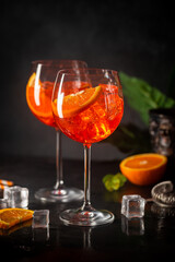 Aperol spritz cocktail in glass with fresh orange on dark background