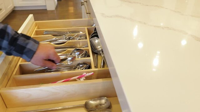 Man opens a kitchen drawer with spoons and forks. Real time video as man&rsquo;s hand is opening a drawer with silver spoons and forks.