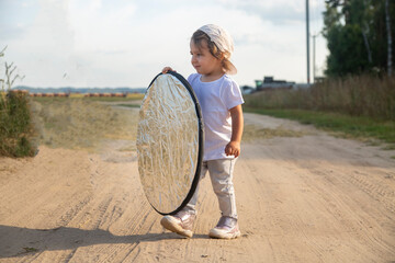 a toddler holds a reflector for the photographer. little helper assistant