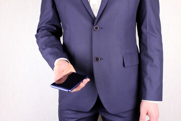 Businessman in a suit with a phone in his hand. Torso of a man in a blue suit with a smartphone