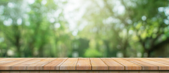 Empty wood table and defocused bokeh and blur background of garden trees with sunlight. product...