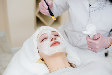 Naklejka premium A young girl in a cosmetology office is undergoing facial skin rejuvenation procedures. Cosmetology.