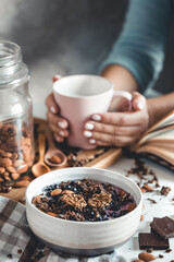 Healthy breakfast, muesli with berries and orange juice served on glass table and books. manicure