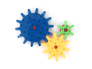 connecting colorful plastic gear wheels (blue yellow green color) isolated on white background, toy...