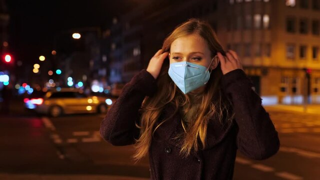 [4k] cute blonde woman putting on ffp2 face mask in streetlight