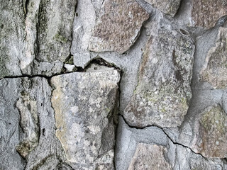 A crack in an old wall with large cobblestones. Stock texture of damage after impact and gravity.