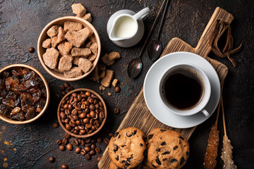 Cup of coffee with chocolate drop cookies, bowls of brown cane lump sugar, crystal sugar sticks,...