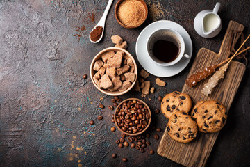 Cup of coffee with chocolate drop cookies, bowls of brown cane lump and granulated sugar, crystal...