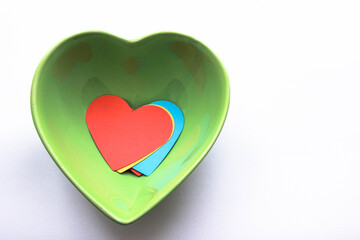 Colorful papers in heart shape inside a heart shaped bowl for valentine's day dinner concept. Top view, copy space for your text.