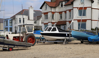 British beach side terraced houses at Rhosneigr, Anglesey, Wales, UK, with boats on the sand in the foreground.