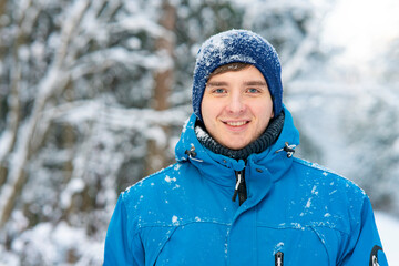 Happy, young man guy smiling on the background of a winter forest in the snow.