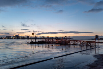Obraz premium Outdoor scenery view of flooded area along riverside of Rhine river in Düsseldorf, Germany during evening time with beautiful sunset and twilight sky.