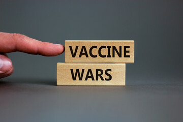 COVID-19 vaccine wars symbol. Concept words 'vaccine wars' on blocks on a beautiful grey background, doctor hand. Medical, COVID-19 vaccine wars concept.