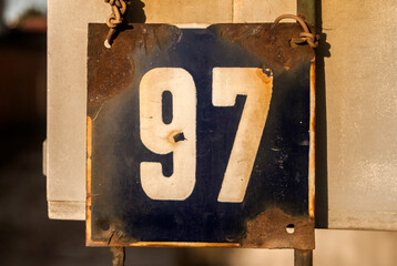 Weathered grunge square metal enameled plate of number of street address with number 97