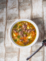 Hot soup in a deep plate with a spoon on chicken broth with vegetables and chicken giblets