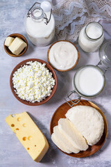 Various fresh dairy products, milk, sour cream, cottage cheese, yogurt and butter on a light stone countertop. Top view flat lay.