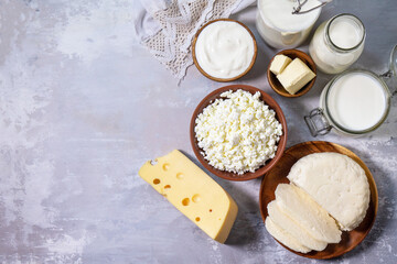 Various fresh dairy products, milk, sour cream, cottage cheese, yogurt and butter on a light stone countertop. Top view flat lay. Copy space.