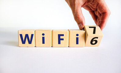 WiFi 6 or 7 symbol. Businessman turns a wooden cube and changes the words WiFi 6 to WiFi 7. Beautiful white background, copy space. Business, technology and WiFi 6 to WiFi 7 concept.