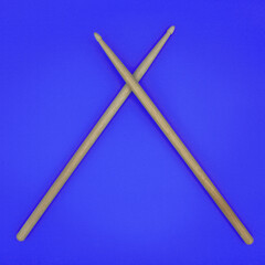 Crossed percussion drumsticks on a blue background.