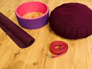 Yoga accessories kit: mat, wheel, yoga strap and zafu. Yoga accessories kit on a wooden floor.