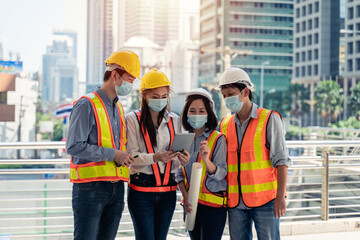 Workers waring surgical mask and safety white head to protect for pollution and virus in workplace during concern about covid pandemic