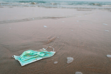 Fototapeta na wymiar used surgical mask was throwed on the beach. enviromental and ecosystem concept