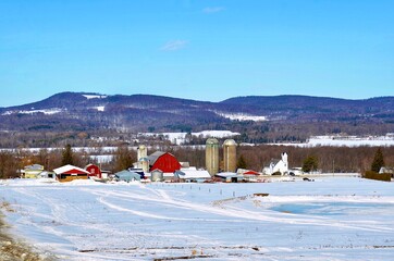 Winter landscape with snow, farm buildings with mountain as background, rural area in New York State 