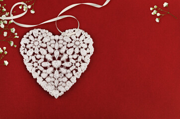 Beautiful white heart with gypsophila flowers and satin ribbon on red textured paper