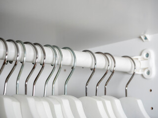 close-up of white wooden hangers in the closet. Selective focus on hooks. equipment for the home