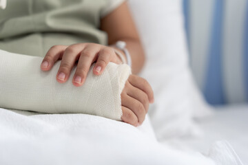 Asian girl treatment in hospital lying on the bed hurting with broken arm back from surgery.