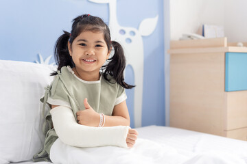 Asian girl treatment in hospital lying on the bed hurting with broken arm back from surgery.