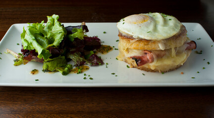 Croque madame or monsieur. Breakfast or brunch favorite: toast, with fried eggs, ham, cheese, and hollandaise sauce. Served with potato hash. Classic French bistro or American restaurant entree.