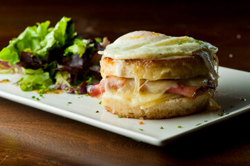 Croque madame or monsieur. Breakfast or brunch favorite: toast, with fried eggs, ham, cheese, and hollandaise sauce. Served with potato hash. Classic French bistro or American restaurant entree.