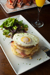Croque madame or monsieur. Breakfast or brunch favorite: toast, with fried eggs, ham, cheese, and hollandaise sauce. Served with potato hash. Classic French bistro or American restaurant entree.