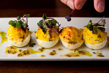Devil eggs. Hard boiled eggs, cut in half and white pipped with yolk mixture. Garnished with...