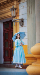 Obraz premium Girl in a vintage dress with an umbrella near mansion