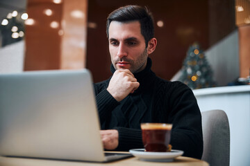 Businessman spending Christmas Eve with laptop in hotel