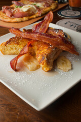French toast. Brioche bread soaked in egg, milk and fried in butter and topper with apples, cinnamon, powdered sugar and syrup. Traditional classical American diner or French Bistro brunch entree.
