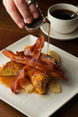 French toast. Brioche bread soaked in egg, milk and fried in butter and topper with apples, cinnamon, powdered sugar and syrup. Traditional classical American diner or French Bistro brunch entree.