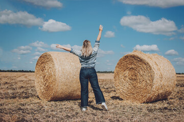 Naklejka na ściany i meble Body positive, high self esteem freedom, concept. Plus size Overweight woman celebrating rising hands to the sky and enjoys life on mowed wheat field with straw bales on sunny summer day