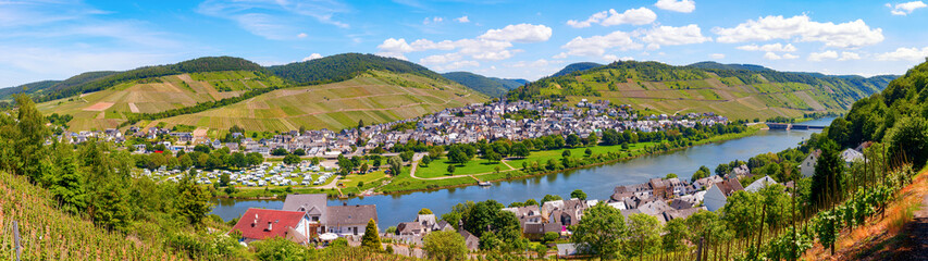 Fototapeta na wymiar Enkirch, Rhineland-Palatinate, Germany. Panoramic view of the river Moselle with the village Enkirch and the surrounding vineyards of the Moselle valley on a sunny afternoon.