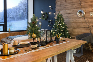 On the eve of the holiday, the interior of the country house is decorated with a New Year tree. large spacious light room decorated with wood with simple wood furniture
