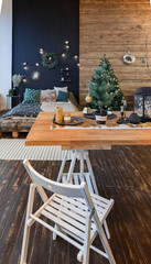 On the eve of the holiday, the interior of the country house is decorated with a New Year tree. large spacious light room decorated with wood with simple wood furniture