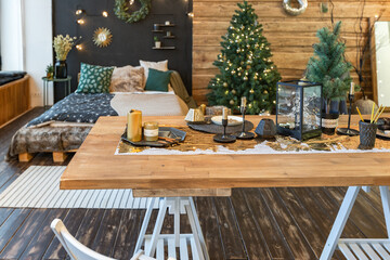 On the eve of the holiday, the interior of the country house is decorated with a New Year tree. large spacious light room decorated with wood with simple wood furniture