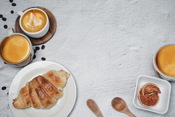 cup of coffee and Fresh baked croissant on white kitchen table. Top view with copyspace for your text.