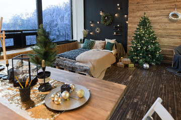 On the eve of the holiday, the interior of the country house is decorated with a New Year tree. large spacious light room decorated with wood with simple wood furniture