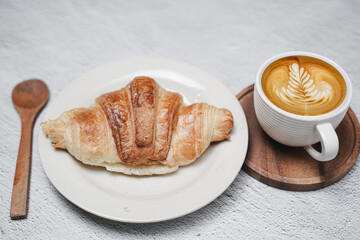 cup of coffee and Fresh baked croissant on white kitchen table. Top view with copyspace for your text.